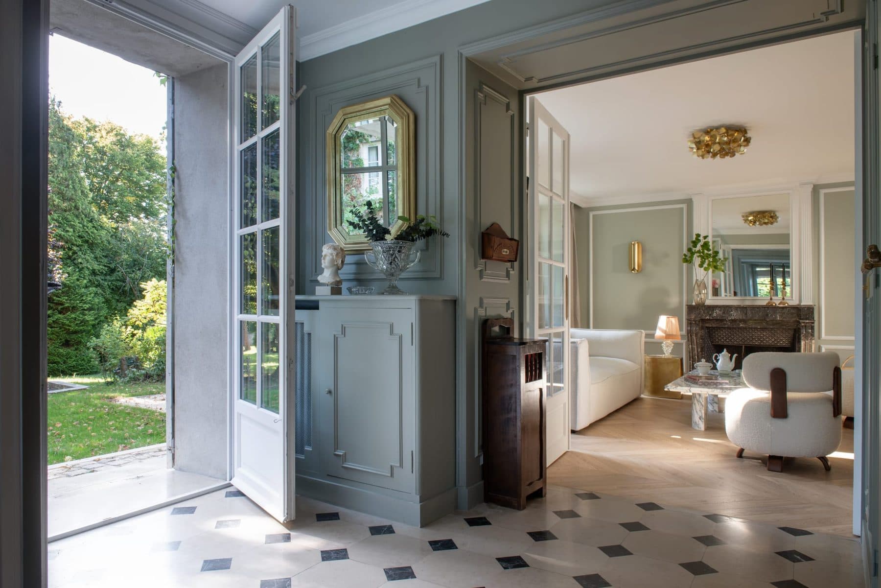 Entrée à damier noir et blanc ouverte sur le jardin